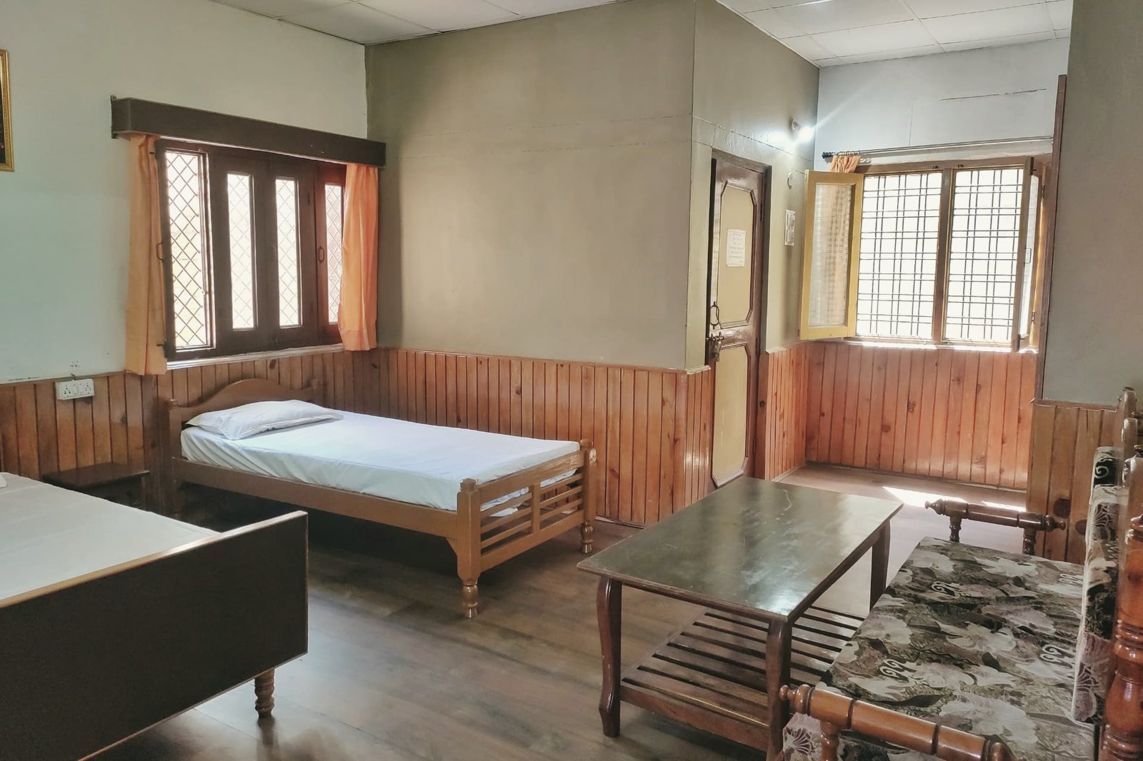 A wood-panelled twin-bed guest room at the ashram with mountain light through the windows