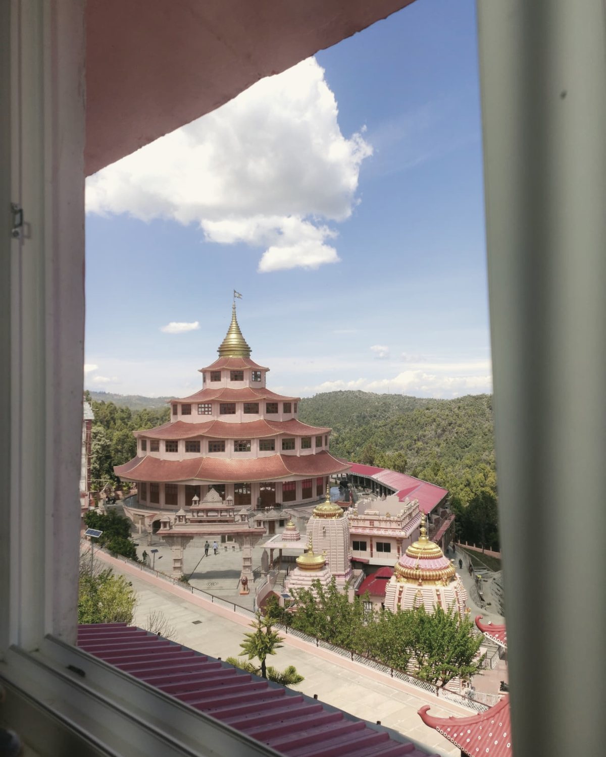 The pagoda temple at Dol Ashram seen through a white window frame from a guest room